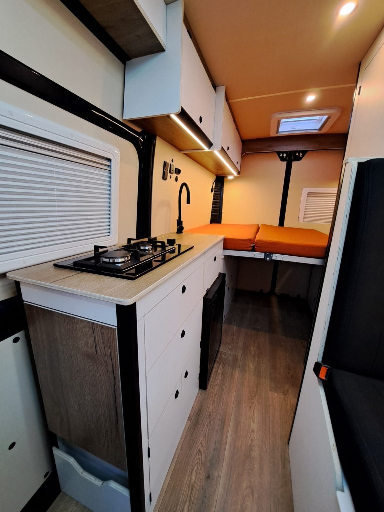 Cocina de furgoneta camper con fogones y cama. Camper Tarraco experto en aislante termico camper.