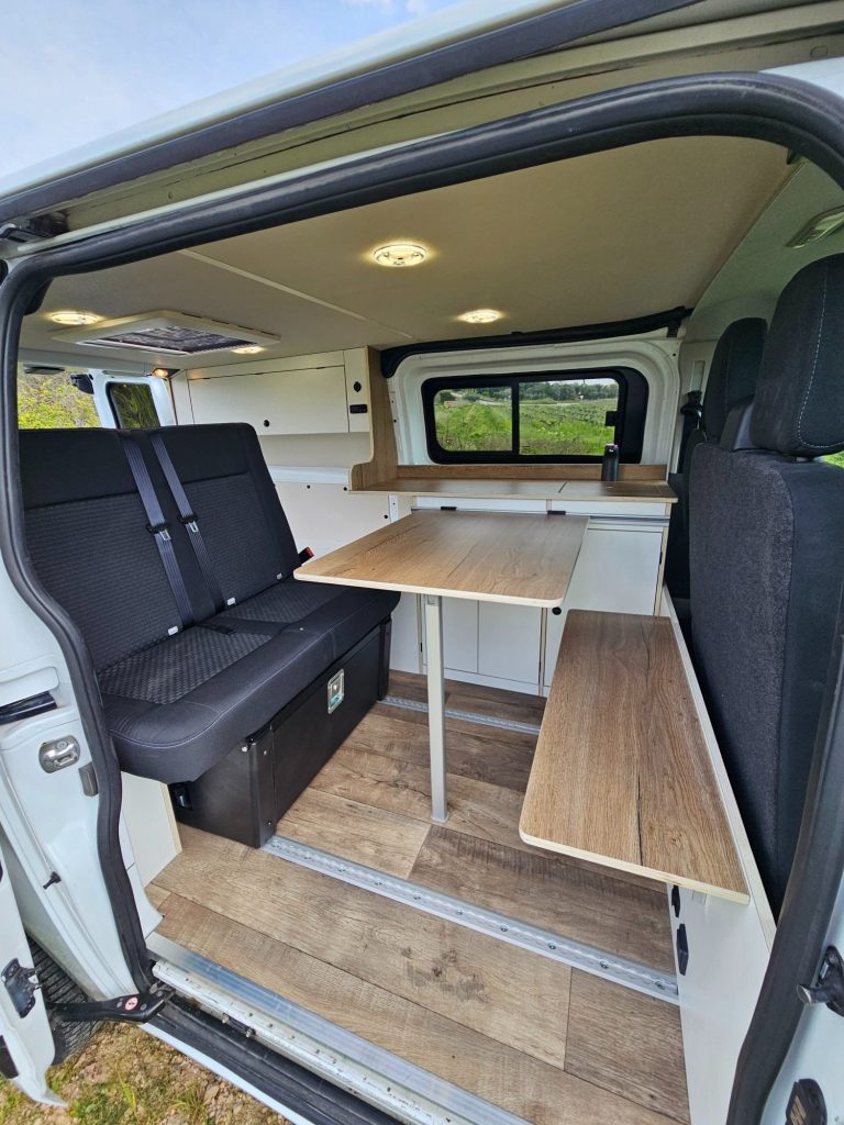 Interior de furgoneta blanca con cama y armarios. Camper Tarraco experto en recambios autocaravanas.