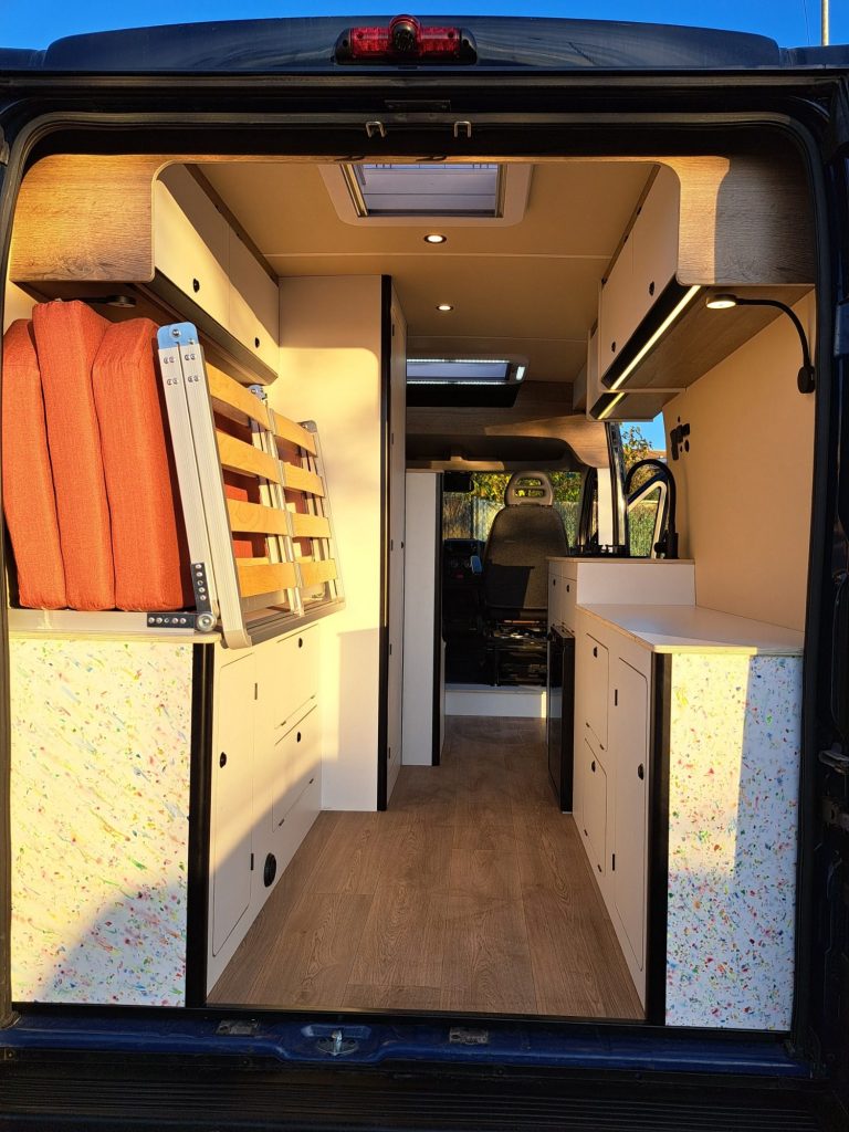 Interior de furgoneta oscura con cama plegada. Camper Tarraco experto en recambios autocaravanas.