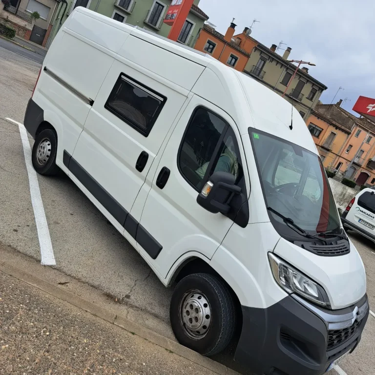 Furgoneta blanca junto a un río y carretera. Camper Tarraco experto en recambios autocaravanas.
