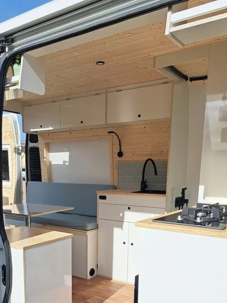 Interior de furgoneta con sofás y mesa central. Camper Tarraco experto en recambios autocaravanas.