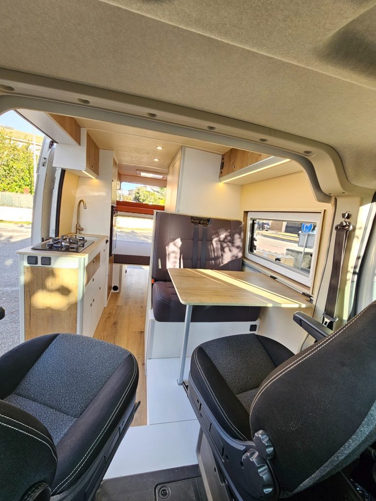Vista interior de furgoneta camper con comedor. Camper Tarraco experto en recambios autocaravanas.